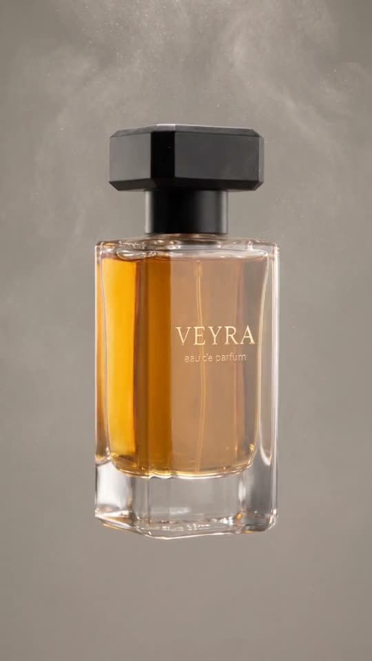 Amber perfume bottle floating in front of a warm grey studio backdrop with haze in the air
